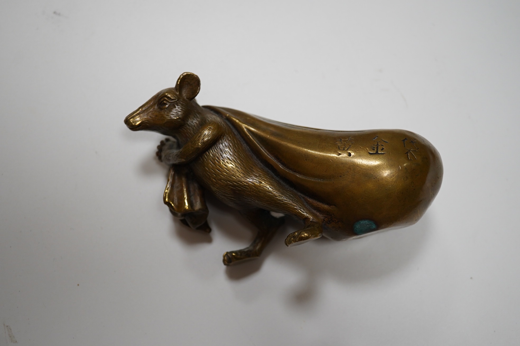 A Chinese bronze rat carrying a sack, signed in casting, 14cm long. Condition - fair